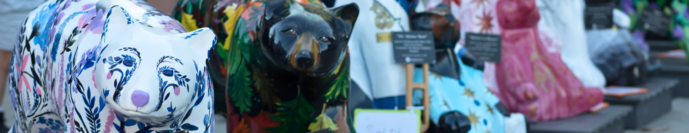 painted fiberglass bears on a plaza with people around 