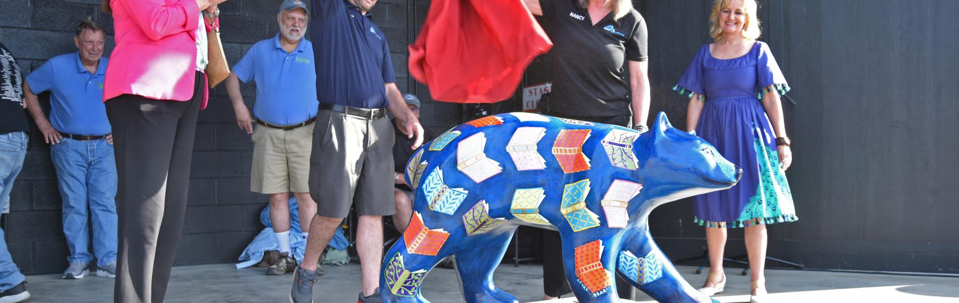 painted fiberglass bears on stage with people removing sheet to reveal bear