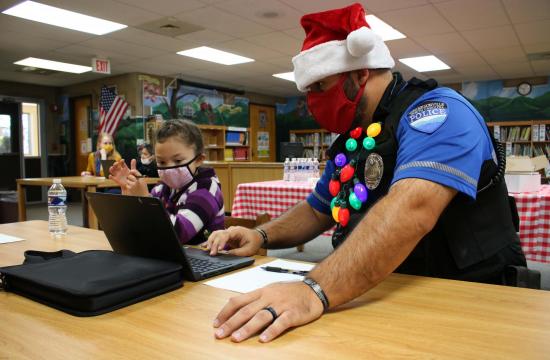officer in santa hat and student at computer