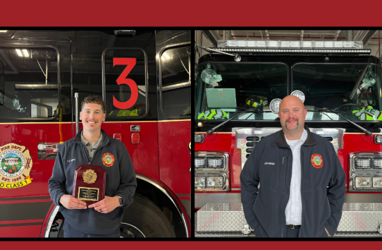 2 firefighters standing in front of a fire engine