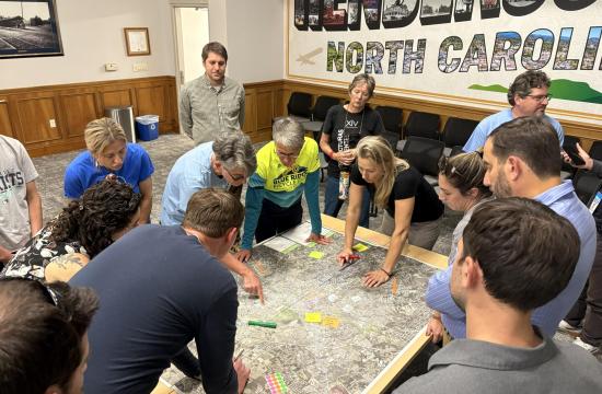 People gathered around and pointing at a map on a table