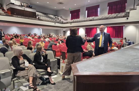 City Manager handing a microphone to a community member in an auditorium