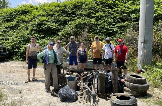 Group of volunteers standing with a pile of tires after a river clean up