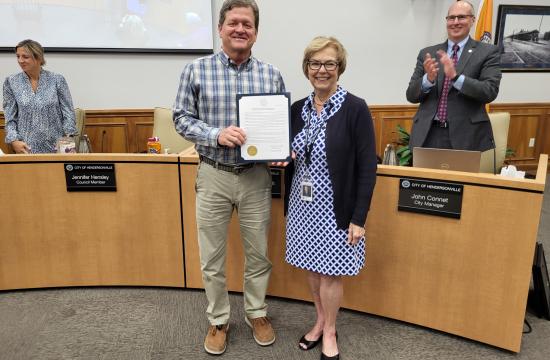 A man holding a certificate, standing beside a woman smiling.