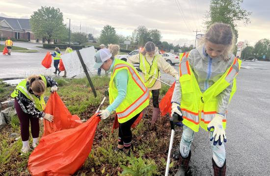 people picking up trash wearing vests