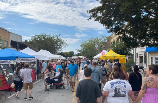 People walking outside on a sunny day during the apple festival.