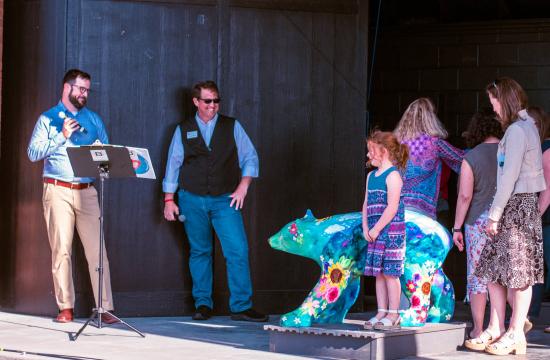 image of a fiberglass art bear and people standing around it on the stage