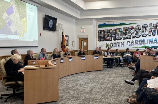 a group of individuals serving on an advisory board sit at a large dais. 
