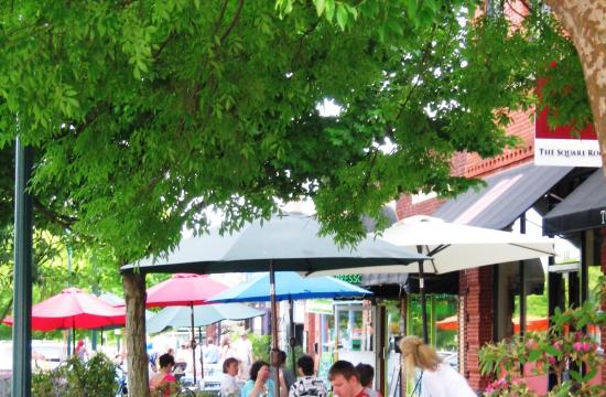 Photo of Main Street, highlighting flower beds, trees, and visitors eating outside.