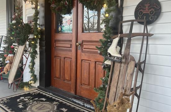 Entryway of a historic inn, decorated with garland, reindeer, and a wooden sleigh.