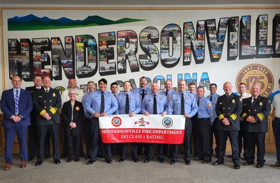 Photo of the Fire Department holding a banner, reading ISO 1 Rating!