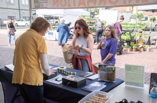 Volunteer working with a customer at the Hendersonville farmers market
