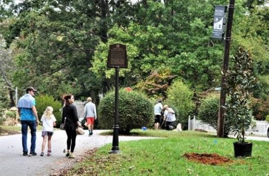3 people walking in area with trees