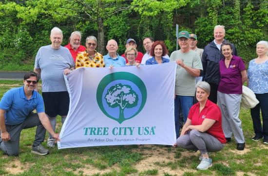 People holding a tree city flag