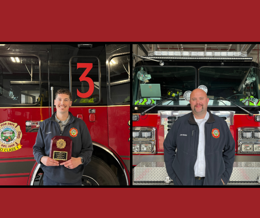2 firefighters standing in front of a fire engine