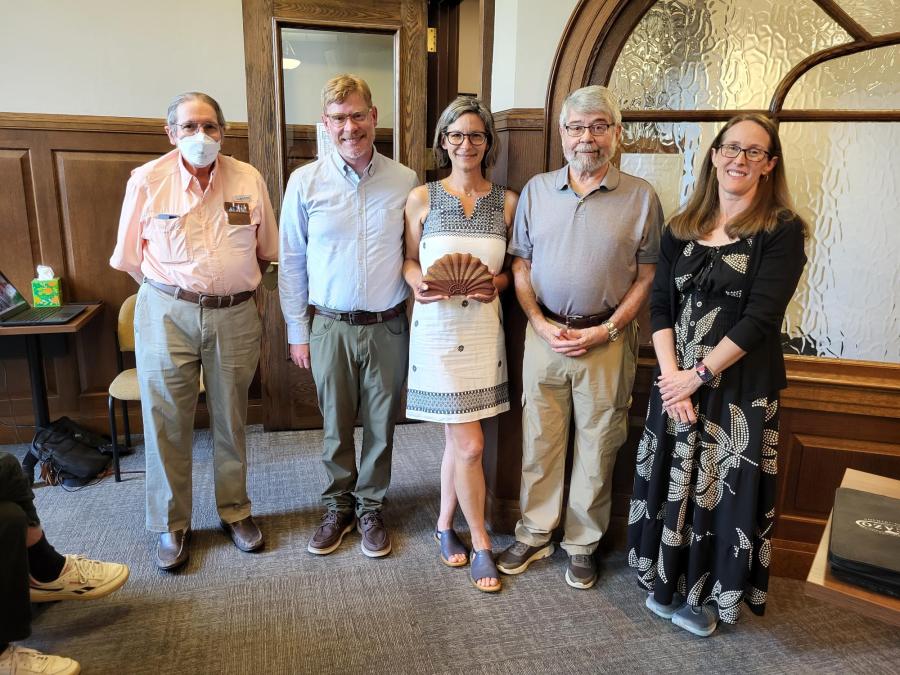 5 people stand with award at a council meeting