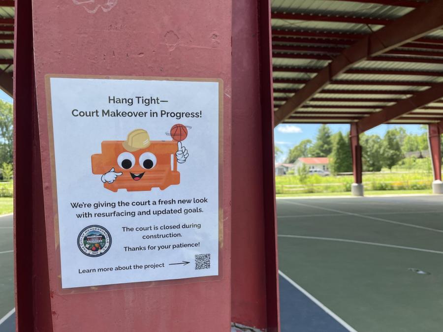 Sign saying basketball court is closed for construction with a cartoon barricade wearing a construction hat