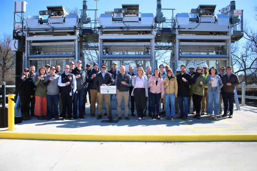 Group of people standing in front of a large water intake holding cups of water
