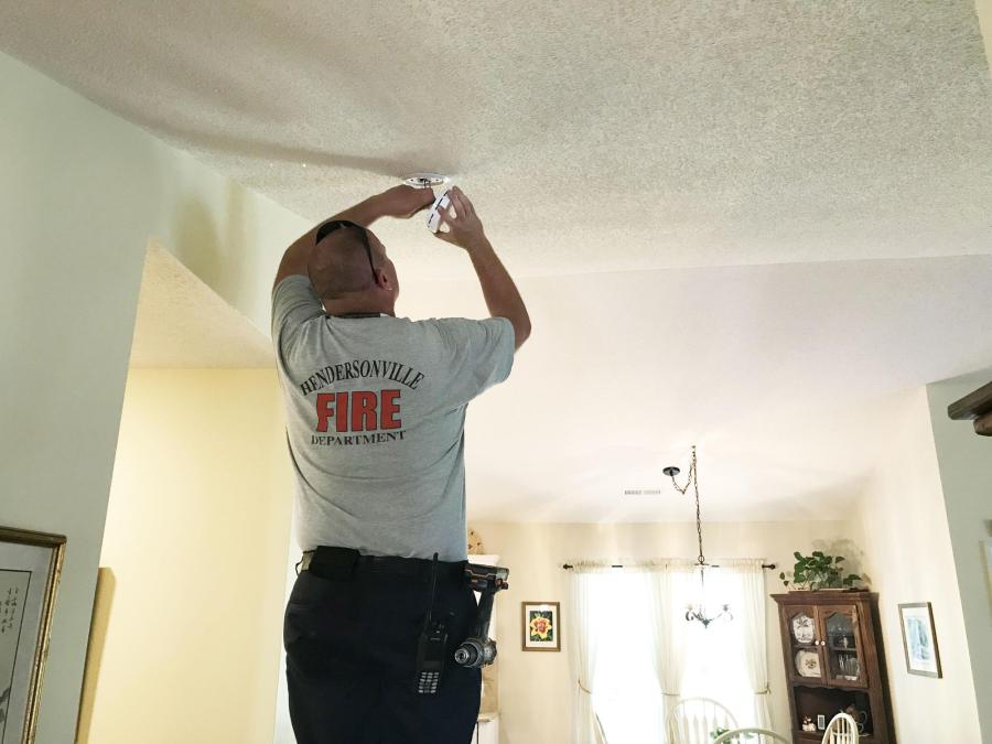 Firefighter installing a smoke alarm