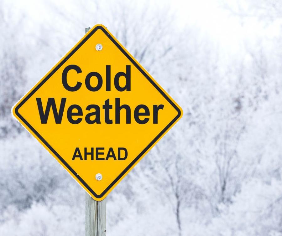 Sign saying cold weather ahead in front of a winter scene