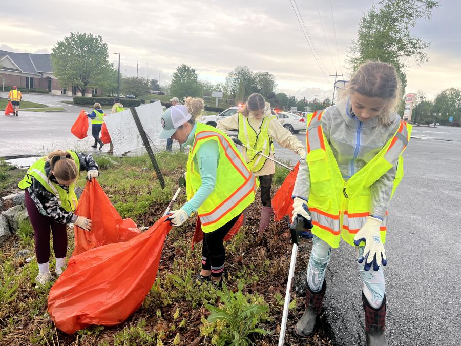 people picking up trash wearing vests