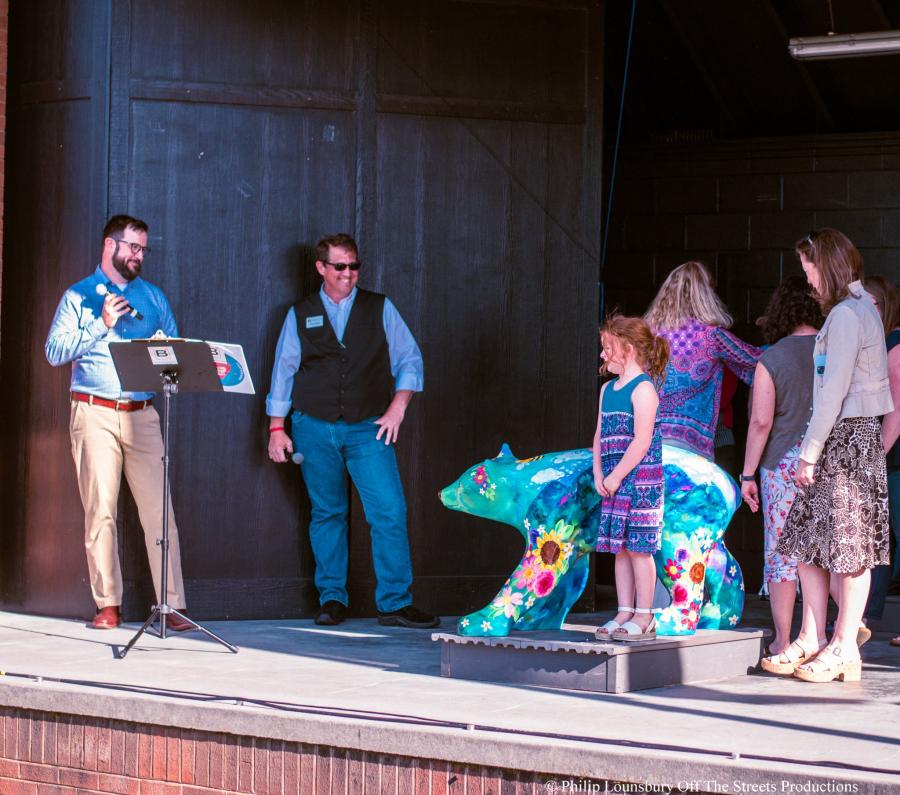 image of a fiberglass art bear and people standing around it on the stage