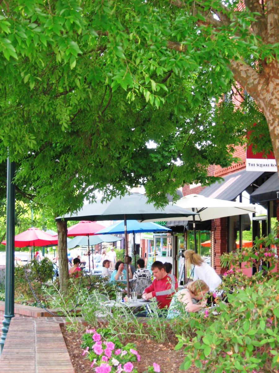 Photo of Main Street, highlighting flower beds, trees, and visitors eating outside.