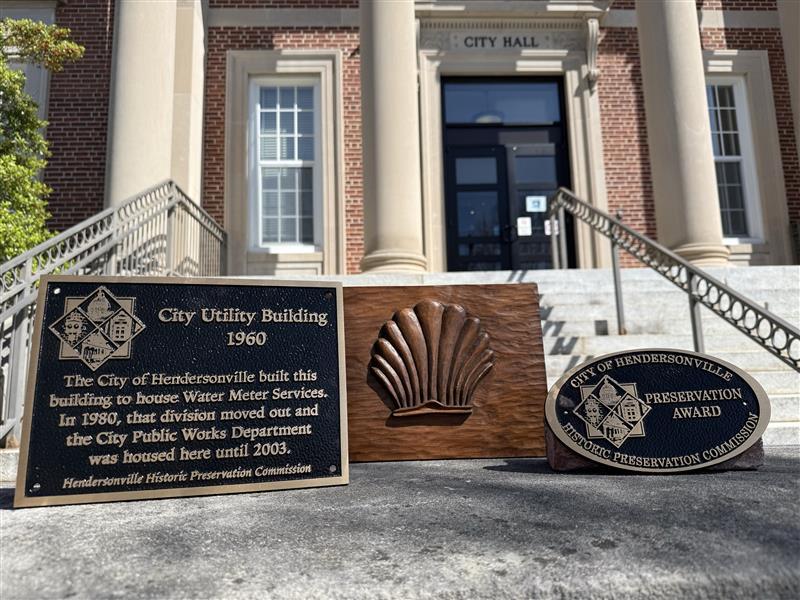 A historic plaque, and Historic Preservation Award, are sitting outside at the foot of the steps to City Hall.