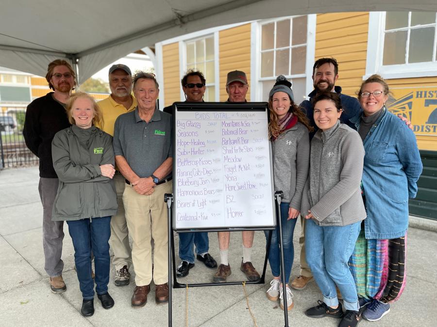 image of volunteers and staff with a bid total board