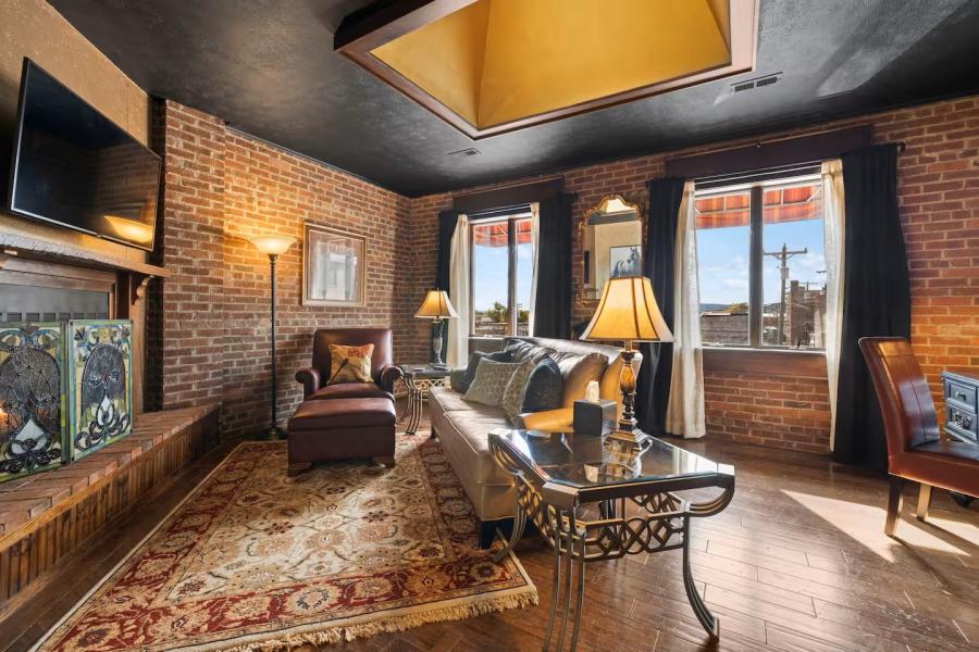A loft in Downtown Hendersonville, showcasing red brick walls, seating and curtains.