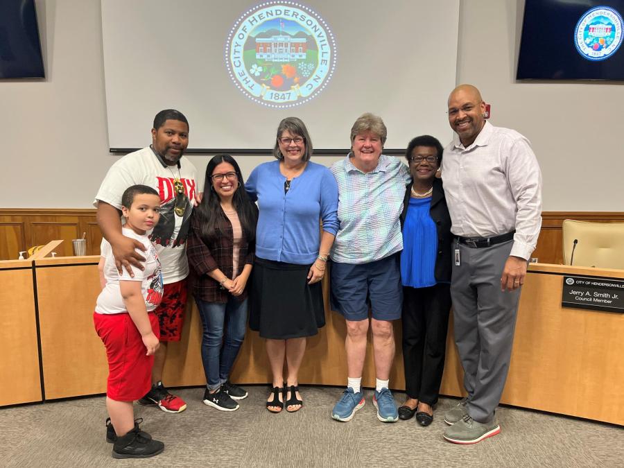 Group of diverse people smiling in front of city logo