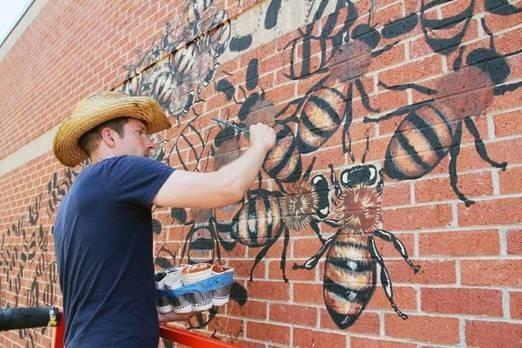 man painting bee mural