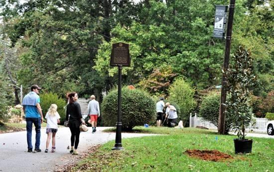 3 people walking in area with trees