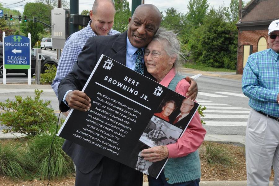 man hugging a woman holding an award