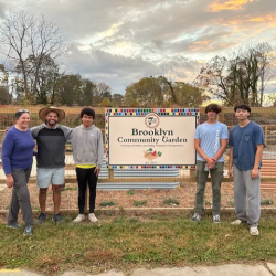Community garden members holding new sign for the garden's expansion and revitalization effort