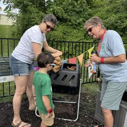 Two women and small boy in front of compost bin