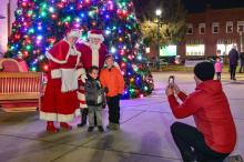 photo of santa and mrs claus in front of tree