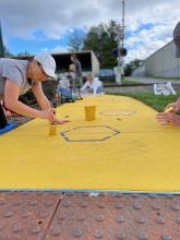 Volunteers painting honeycombs on sidewalk