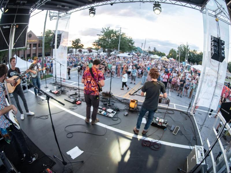 bands playing on a stage in front of an outdoor crowd
