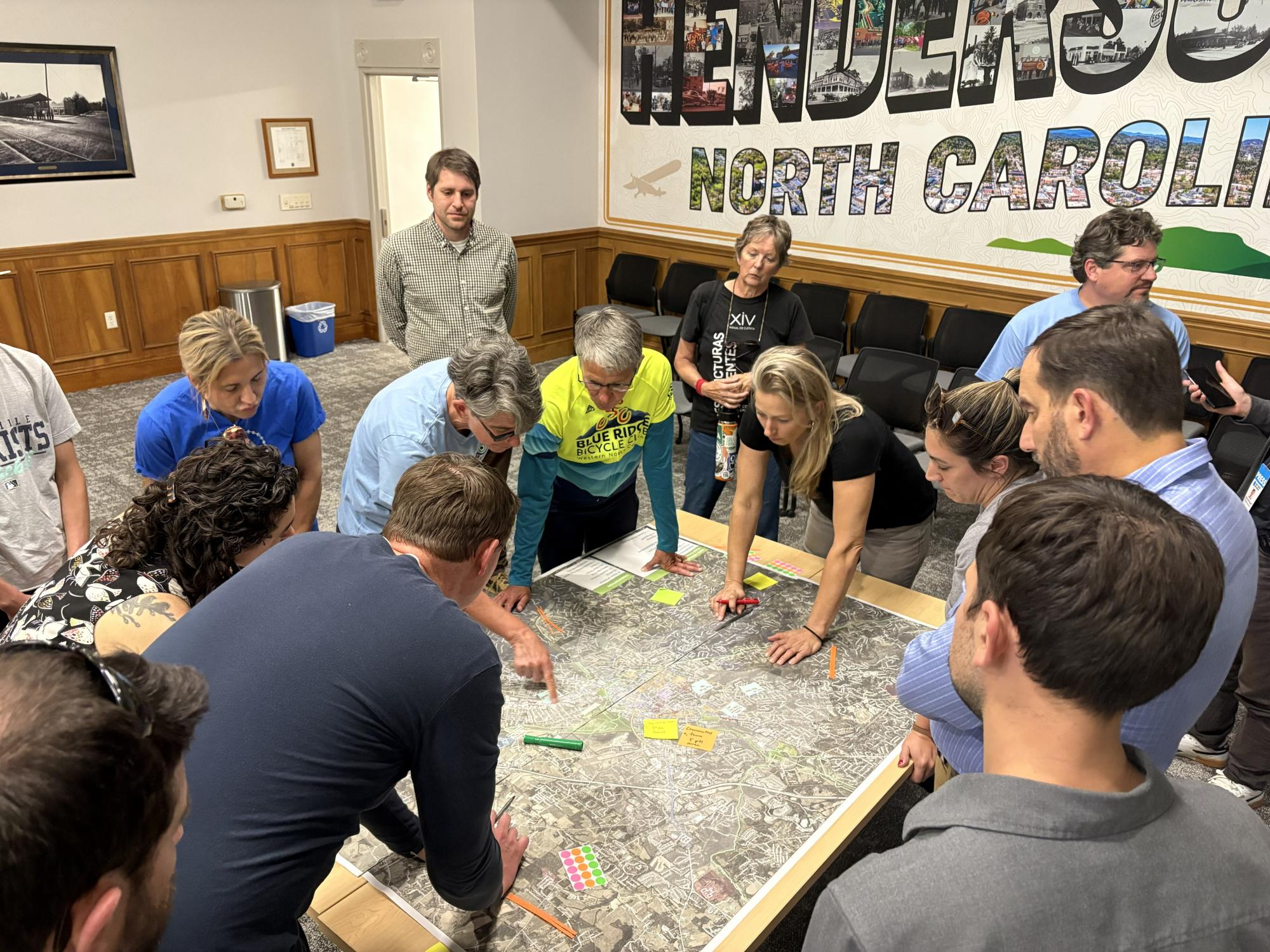 People surrounding a map pointing at bike routes