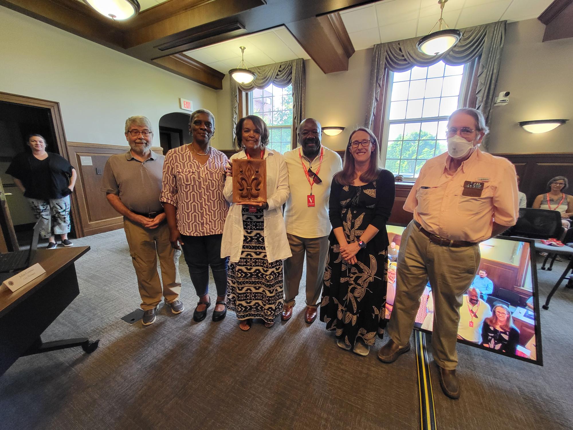 6 people stand with award at a council meeting