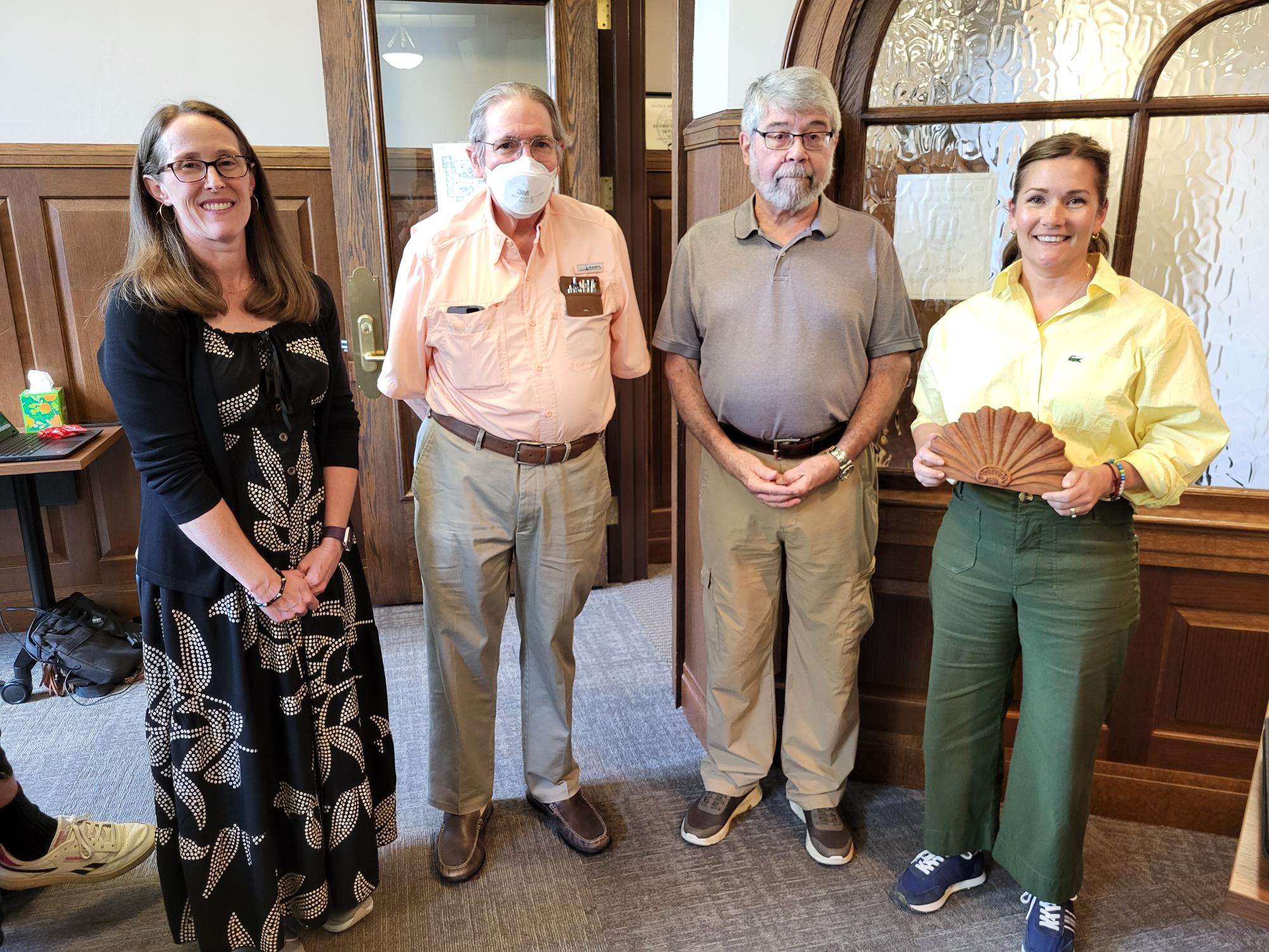 4 people stand with award at a council meeting