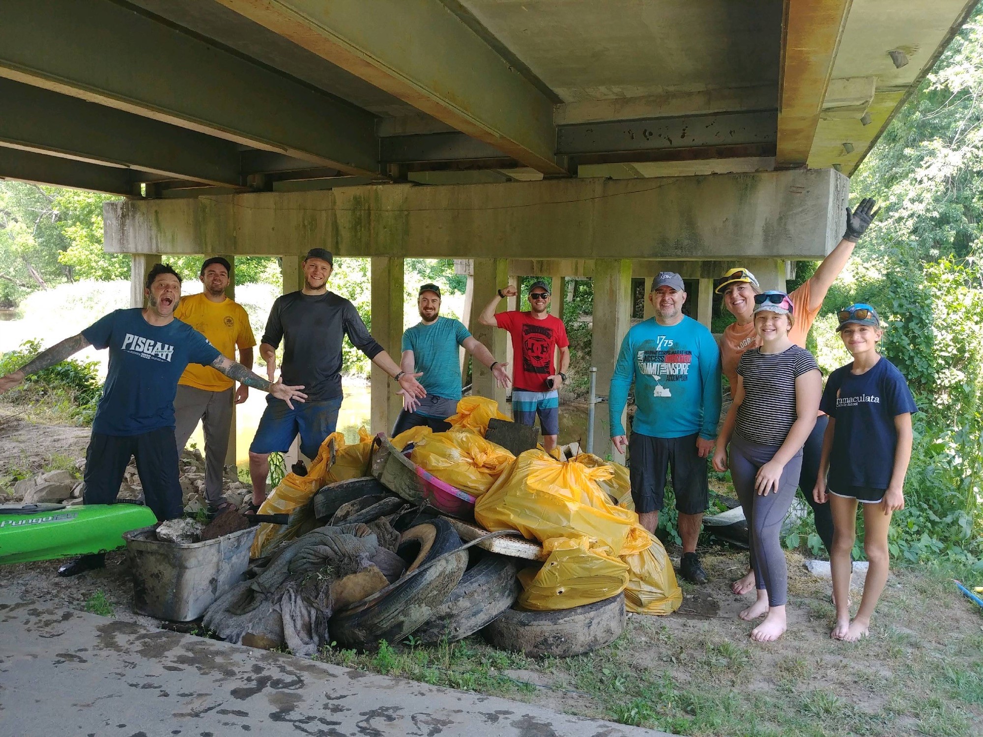 Photo of people next to a pile of trash cleaned out of Mud Creek