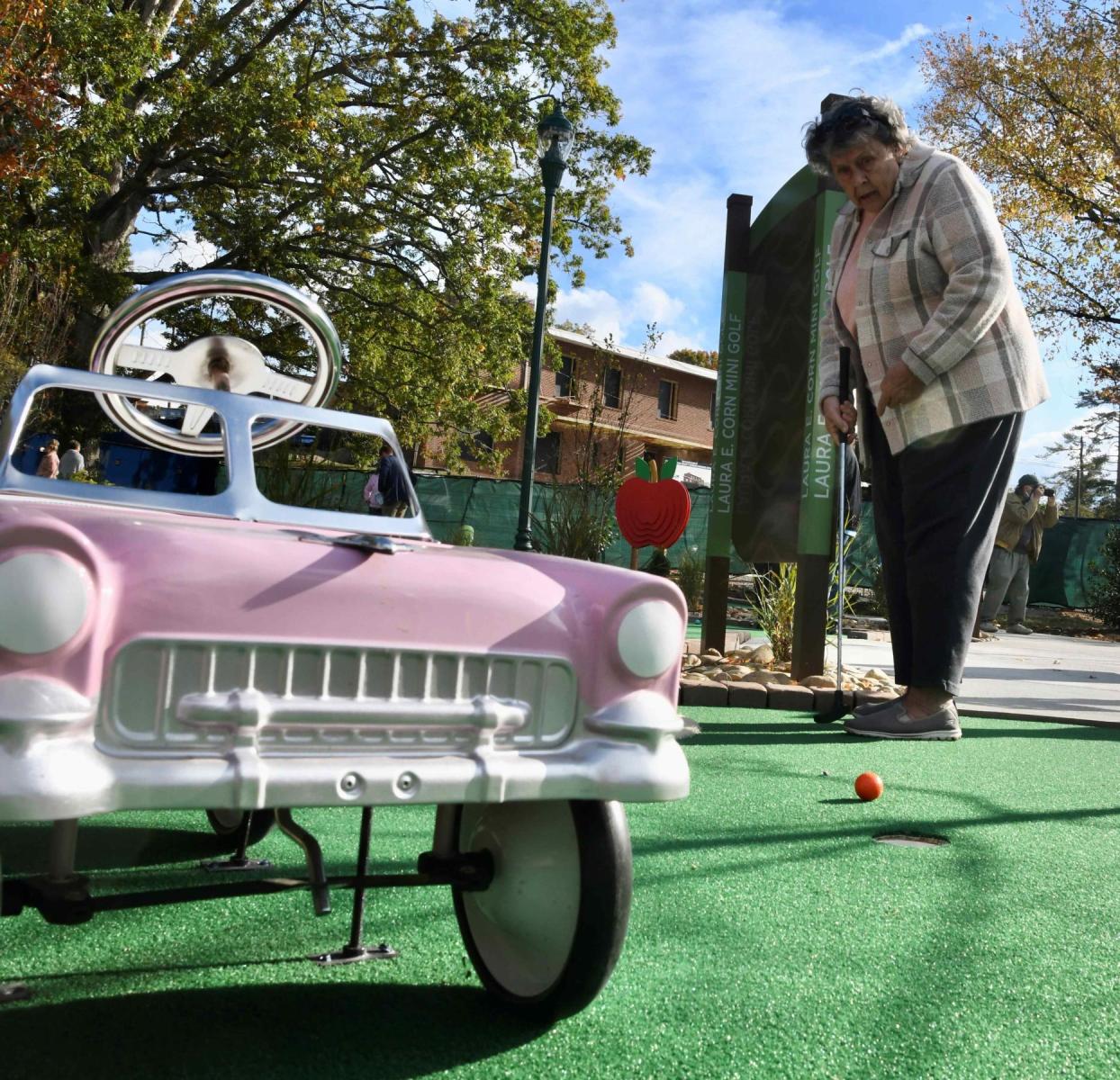 A woman playing mini golf beside a pink vintage car course feature