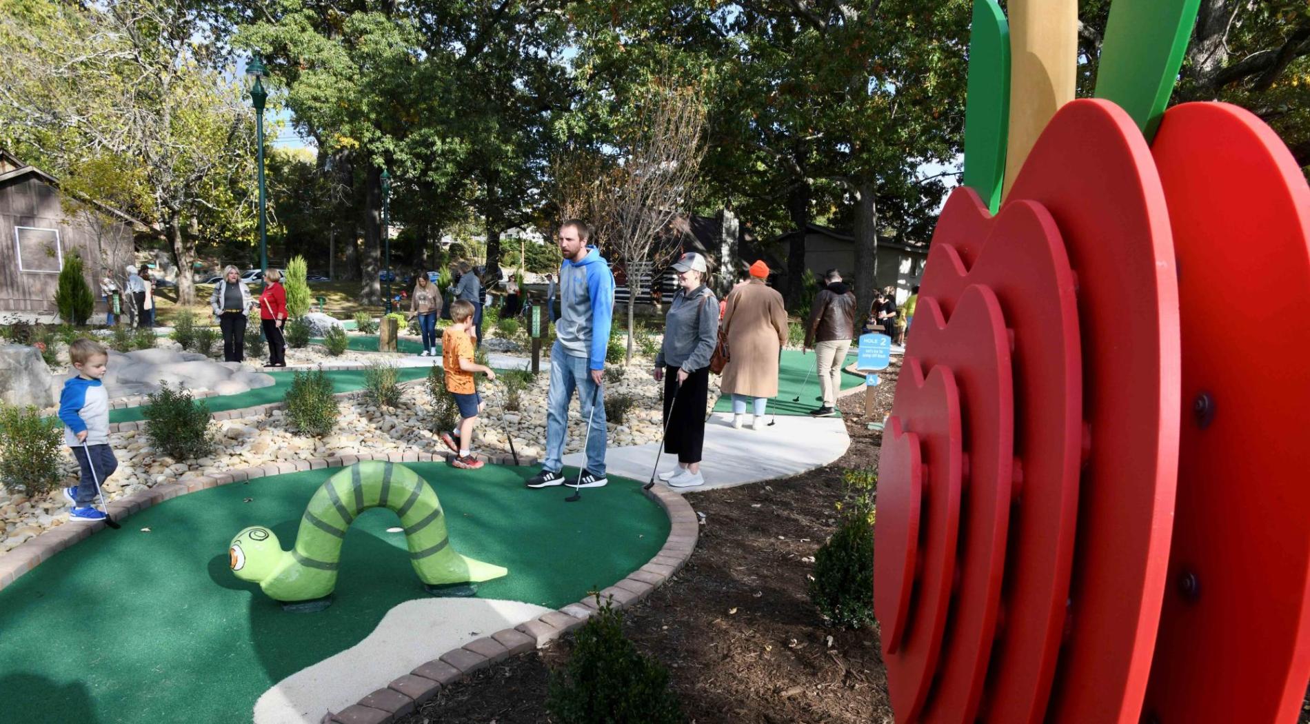 People golfing next to a large apple feature made by the Apple Country Woodcrafters