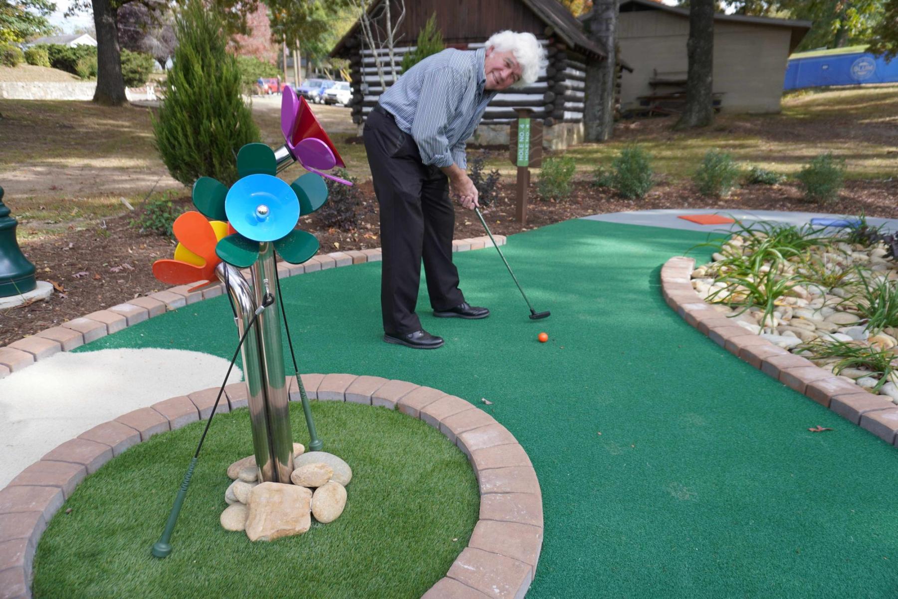 Tommy Shipman playing mini golf near a musical flower installation