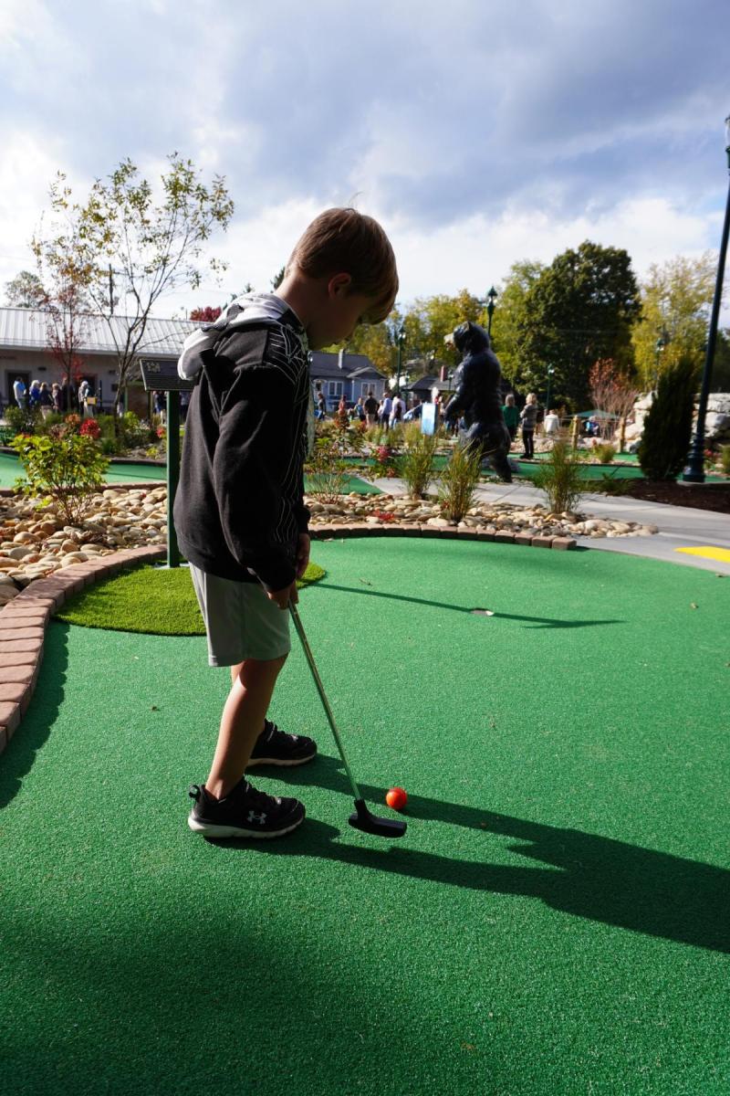 A boy putts on a mini golf green