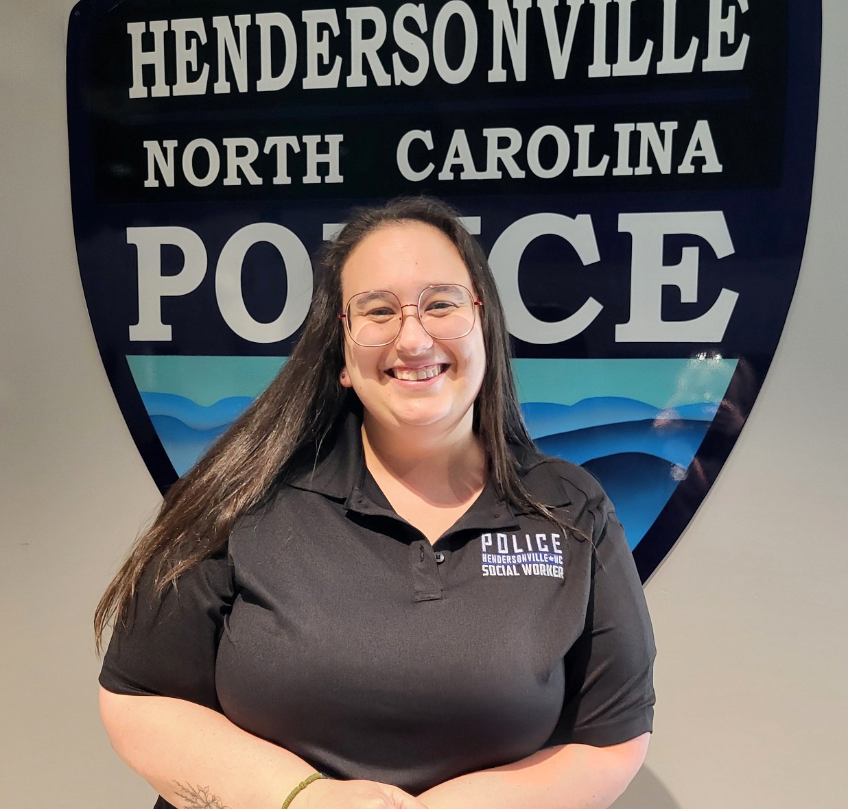 Cammy Holt smiling in front of a police department logo