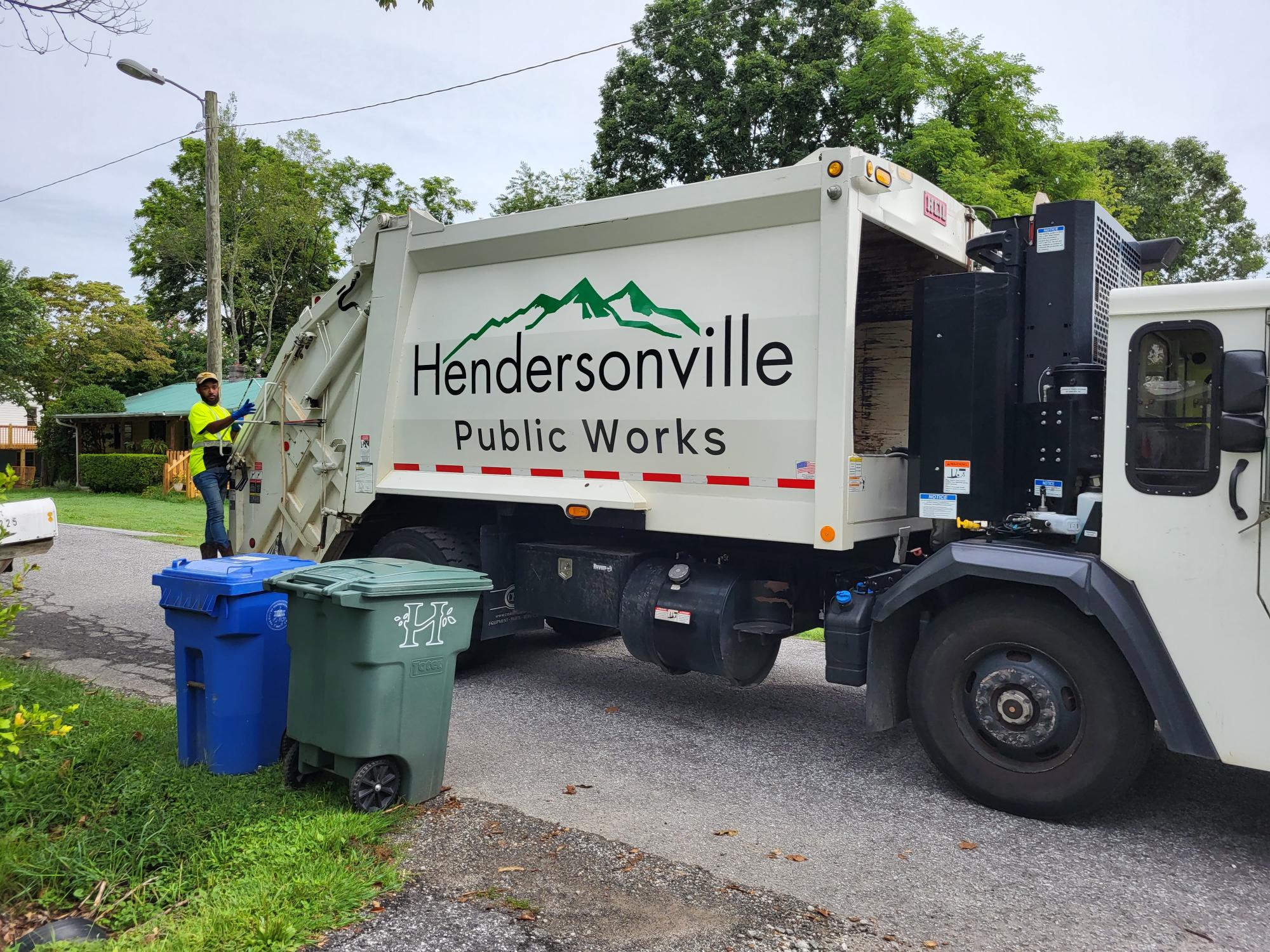 Garbage and recycling truck with man on back of truck