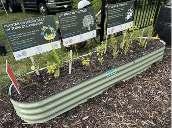 Pollinator garden bed with educational signs in background